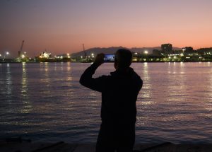 Man photographing Malaga harbour during a sunset